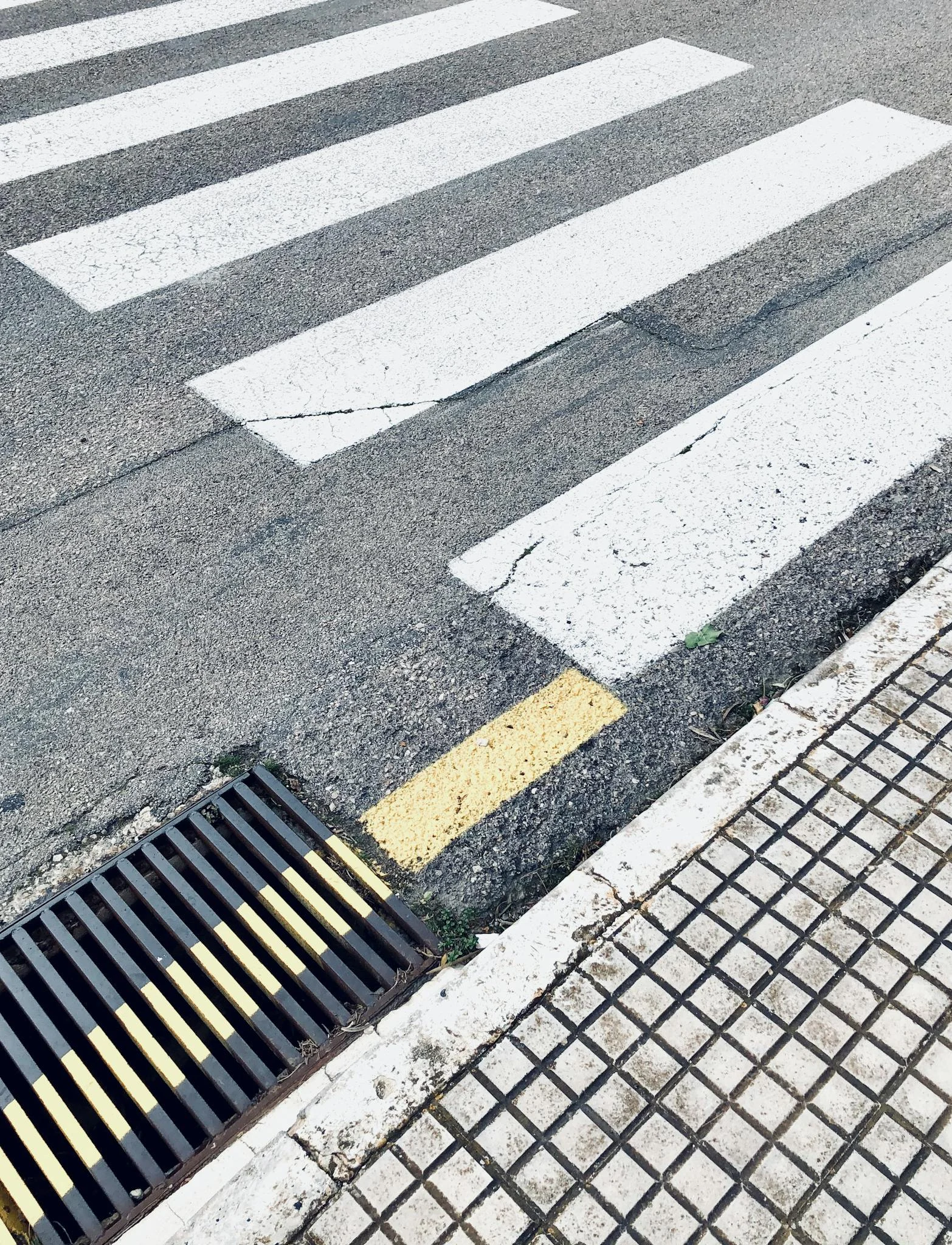 crosswalk marked on asphalt road near sewer
